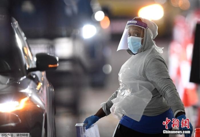 當(dāng)?shù)貢r(shí)間12月18日，英國(guó)政府公布的數(shù)據(jù)顯示，當(dāng)天英國(guó)新增奧密克戎毒株感染病例10059例。鑒于奧密克戎毒株感染病例激增，住院人數(shù)不斷上升，倫敦市長(zhǎng)宣布倫敦進(jìn)入“重大事故”狀態(tài)。圖為倫敦的一個(gè)免下車檢測(cè)中心，一名醫(yī)務(wù)工作者正準(zhǔn)備對(duì)司機(jī)進(jìn)行核酸檢測(cè)。