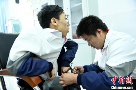 江西省南康中學(xué)北校區(qū)的高三學(xué)生朱金祥(右)正在給鐘華強(qiáng)(左)系好鞋帶。 卓忠偉 攝