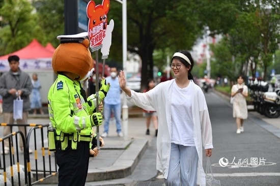 6月7日上午9時(shí)，隨著鈴聲的響起，2023年江西高考正式開(kāi)考，江西省的53.57萬(wàn)考生以縣（區(qū)）為單位隨機(jī)安排在全省256個(gè)考點(diǎn)、18968個(gè)考場(chǎng)參加高考。圖為“小熊交警”和考生擊掌鼓勵(lì)。 人民網(wǎng)記者 時(shí)雨攝