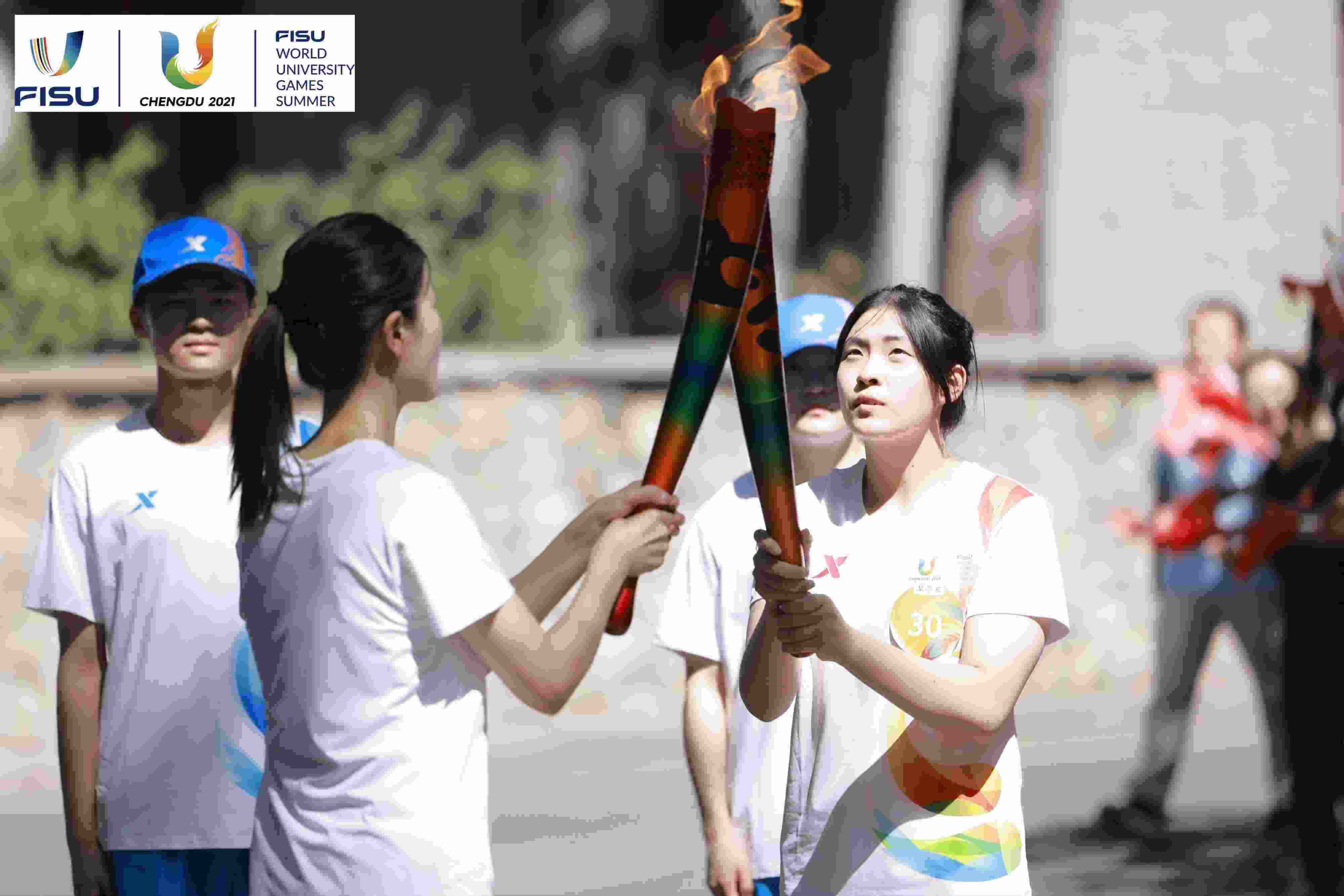 兩名大運(yùn)會(huì)火炬手進(jìn)行火炬?zhèn)鬟f。 圖片來(lái)源：成都大運(yùn)會(huì)執(zhí)委會(huì)供圖