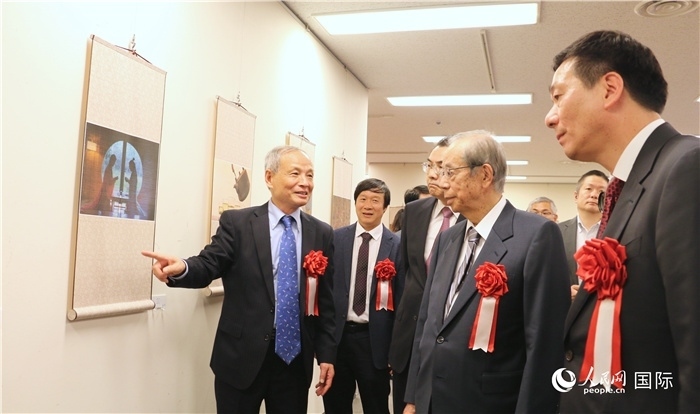 “湖州印象”攝影展主創(chuàng)、世界華人攝影協(xié)會副會長馮學敏向吳江浩大使、福田康夫前首相等嘉賓介紹展出作品。（人民網(wǎng) 許可攝）