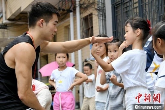 圖為大學生志愿者在組織孩子們參加體育健身活動。廖光福 攝