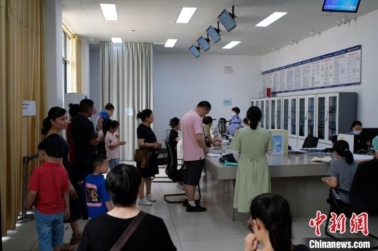 圖為在戶籍辦證廳內(nèi)排隊等待的家長和孩子。劉俊聰 攝