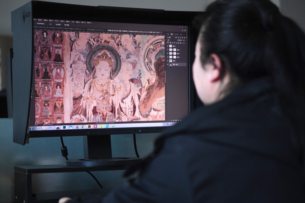 敦煌研究院文物數(shù)字化保護(hù)團(tuán)隊(duì)圖像處理人員年海麗在拼接壁畫(huà)圖像（2023年4月25日攝）。數(shù)字化探索為莫高窟的保護(hù)與傳承開(kāi)辟了全新路徑，數(shù)字技術(shù)讓敦煌文物走出洞窟，跨出國(guó)門(mén)，走向“永久保存、永續(xù)利用”。新華社記者 陳斌 攝
