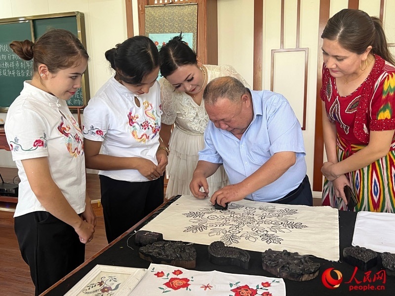 國家級非物質(zhì)文化遺產(chǎn)模戳印花布技藝傳承人吾吉阿西木?吾舒爾展示模戳印花布的制作過程。人民網(wǎng)記者 常雪梅攝