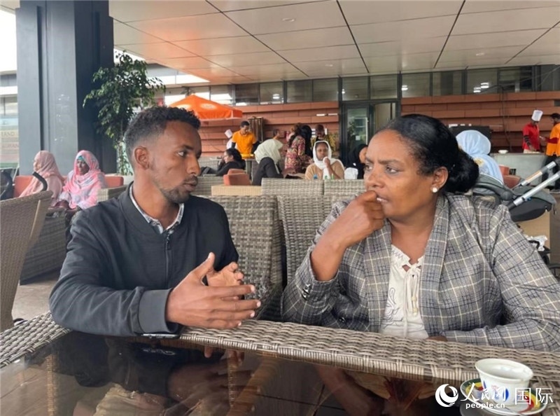 約漢斯（圖左）與德貝拉在友誼廣場(chǎng)咖啡廳交談。人民網(wǎng)記者 趙艷紅攝