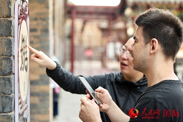 選手安德烈（俄羅斯）在老師指導(dǎo)下學(xué)習(xí)墻壁上張貼的生僻字。人民網(wǎng) 盧鵬宇攝