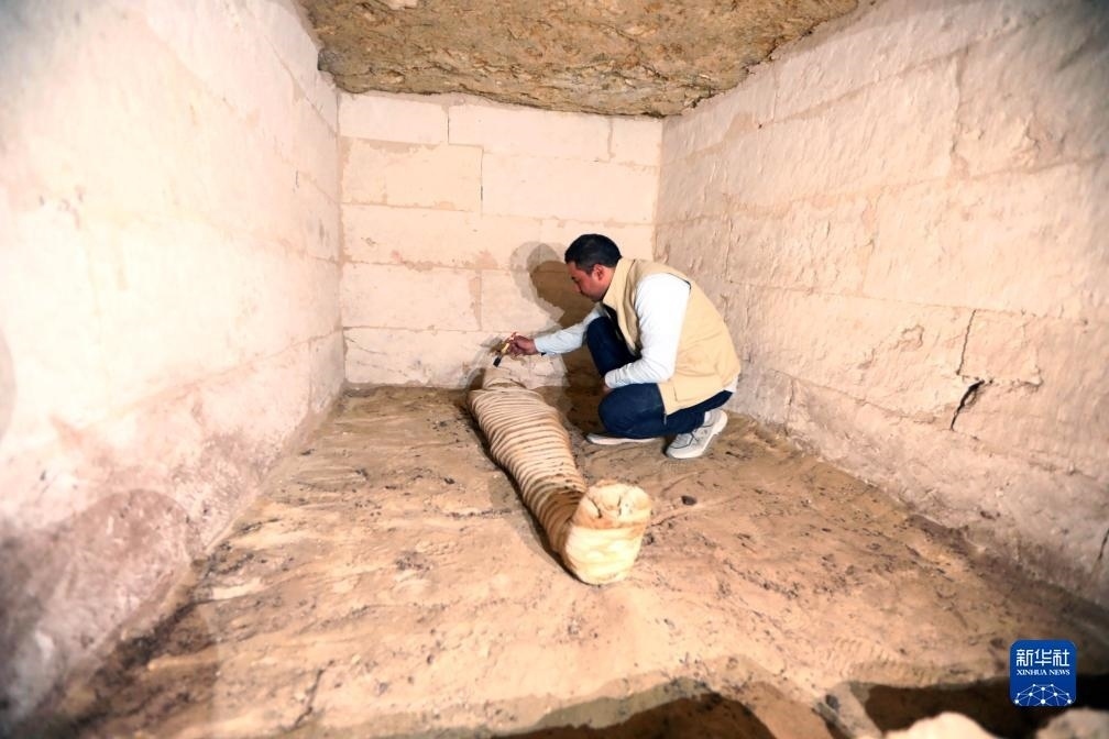 10月15日，在埃及明亞省考古現(xiàn)場(chǎng)，考古人員清理一座石鑿墓中的木乃伊。新華社發(fā)（艾哈邁德·戈馬攝）