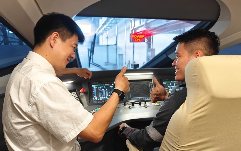 8月25日，在印度尼西亞萬隆的雅萬高鐵德卡魯爾動車所內(nèi)，中國師傅穆振（左）在向印尼火車司機(jī)塞蒂亞萬講解動車組出庫前的上電作業(yè)。