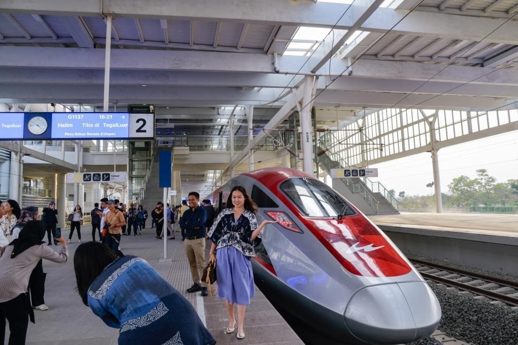 10月17日，在印度尼西亞萬隆德卡魯爾站，乘客在站臺上和雅萬高鐵高速動車組列車合影。