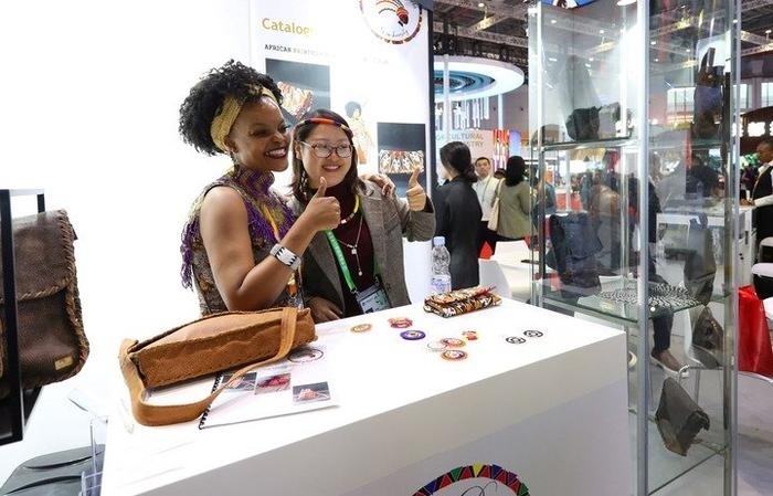 11月6日，一位參觀者（右）在第六屆進博會國家展南非展臺試戴傳統(tǒng)首飾。