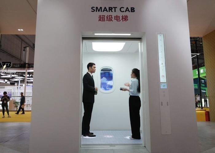 11月5日，工作人員（右）在第六屆進博會上向參觀者介紹奧的斯公司全新推出的超級電梯。