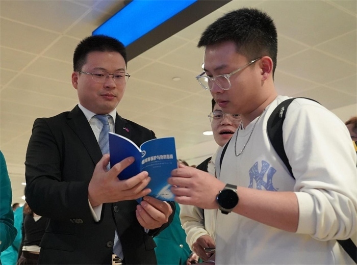 工作人員（左一）在發(fā)放《中國(guó)領(lǐng)事保護(hù)與協(xié)助指南》。 中國(guó)駐迪拜總領(lǐng)事館供圖