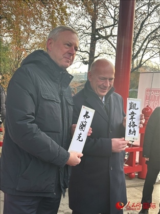 柏林市長韋格納（右）、動物園監(jiān)事會主席布魯克曼（左）手持中國文化中心工作人員現(xiàn)場手書的中文名字。人民網(wǎng)記者 徐馨攝