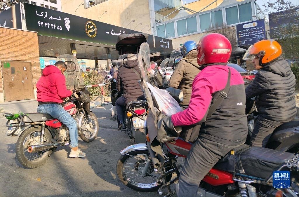 12月18日，摩托車在伊朗首都德黑蘭的一家加油站外等待加油。新華社記者 沙達提 攝