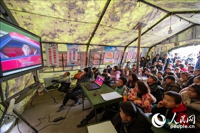 12月22日，在積石山縣大河家鎮(zhèn)大河村安置點(diǎn)，陸軍76集團(tuán)軍某旅搭建的“臨時學(xué)?！眱?nèi)，小朋友正在看動畫片。人民網(wǎng)記者 翁奇羽攝