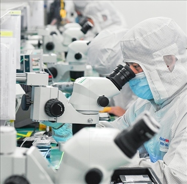 在位于武漢中國(guó)光谷的光電器件研發(fā)制造商——武漢光迅科技股份有限公司生產(chǎn)車間內(nèi)，技術(shù)人員在光模塊生產(chǎn)線作業(yè)（2023年4月11日攝）。程敏攝/本刊