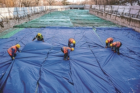 1月3日，房山區(qū)東風(fēng)街道，工人正在修復(fù)的河道內(nèi)給混凝土鋪設(shè)保溫布。