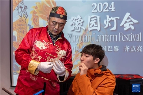 1月28日，在上海豫園舉行的民俗活動(dòng)上，美國(guó)馬斯卡廷中學(xué)學(xué)生在非遺傳承人的指導(dǎo)下吹糖偶。 新華社記者 王翔 攝