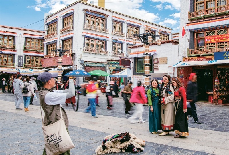 千年八廓街，見證民族團(tuán)結(jié)。2021年7月，習(xí)近平總書記來到位于西藏拉薩老城區(qū)的八廓街，感慨地說：“千年八廓街，是我們各民族建起來的八廓街。各民族文化在這里交流交往交融，我們中華民族的大家庭在這里其樂融融?！眻D為2023年6月13日，游客身著藏裝在八廓街拍照留念。 新華社記者 姜帆/攝