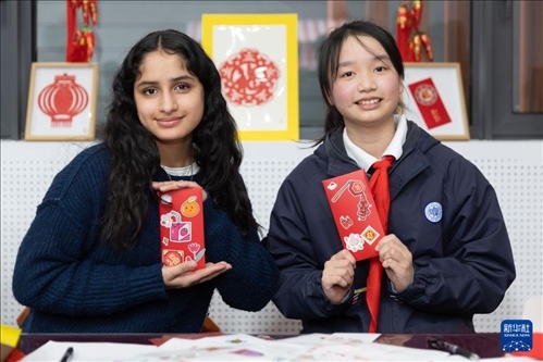 1月28日，美國(guó)馬斯卡廷中學(xué)學(xué)生（左）和復(fù)旦大學(xué)第二附屬學(xué)校學(xué)生展示互相送出的寫有寄語祝福的紅包。 新華社記者 王翔 攝