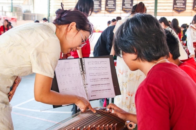 志愿者教師指導(dǎo)學(xué)生彈奏古箏?；顒又鬓k方供圖