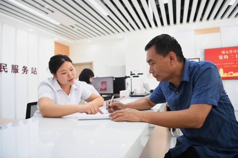 2023年5月23日，河北雄安新區(qū)容東片區(qū)南文營(yíng)社區(qū)居民（右）在社區(qū)便民服務(wù)站辦理業(yè)務(wù)。