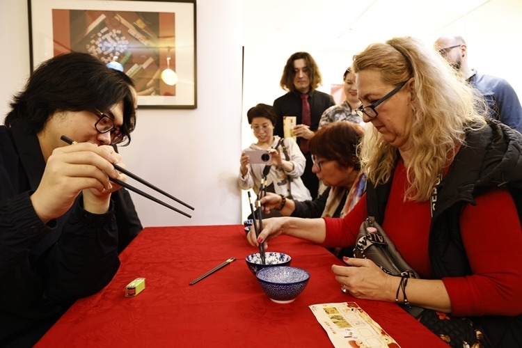 羅馬尼亞觀眾體驗(yàn)用筷子夾花生。中國(guó)文化中心供圖