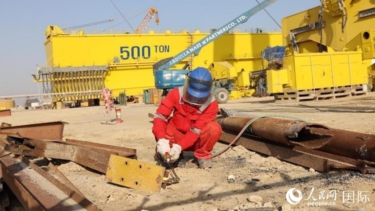 工人正在龍門吊吊裝現(xiàn)場切割金屬件。人民網(wǎng)記者管克江攝