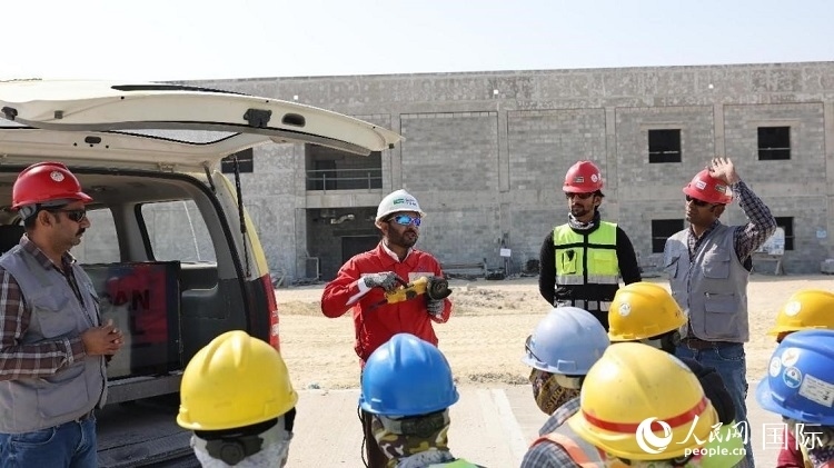 穆薩瓦爾(圖中紅衣人）現(xiàn)場演示工具操作規(guī)范。人民網(wǎng)記者 管克江攝