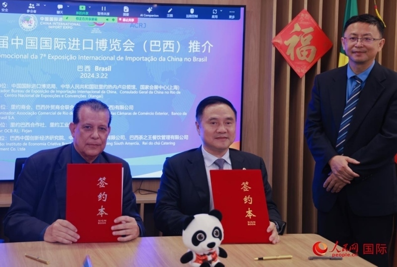 巴西外貿(mào)商會聯(lián)合會會長阿代爾·羅伯托（左）與中國國際進(jìn)口博覽局副局長吳政平（中）現(xiàn)場簽訂協(xié)議。人民網(wǎng)記者 宋亦然攝