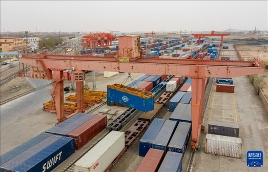 4月21日，二連浩特鐵路口岸龍門吊吊裝中歐班列集裝箱（無人機照片）。 新華社發(fā)（張海峰攝）