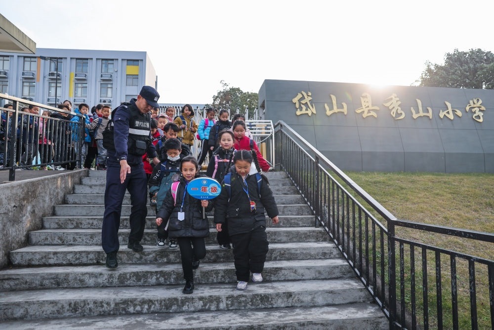 2023年12月20日，秀山派出所民警在秀山小學(xué)放學(xué)時(shí)間參與“護(hù)學(xué)崗”維持秩序，同時(shí)接獨(dú)自放學(xué)的學(xué)生去“民生小鋪”。浙江省舟山市岱山縣公安局秀山派出所聯(lián)合鄉(xiāng)鎮(zhèn)、社區(qū)成立“民生小鋪”，為當(dāng)?shù)鼐用?、外來?wù)工人員及其子女等服務(wù)，協(xié)助解決外來務(wù)工人員在工作、生活等方面的矛盾和問題，助力鄉(xiāng)鎮(zhèn)基層治理。新華社記者 徐昱 攝