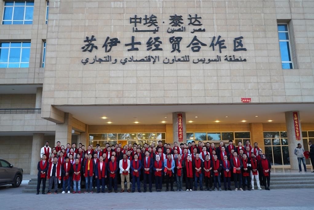 2024年2月11日，在位于埃及蘇伊士省的中?！ぬ┻_(dá)蘇伊士經(jīng)貿(mào)合作區(qū)，中埃員工在合作區(qū)辦公大樓前合影拜年。新華社發(fā)（泰達(dá)合作區(qū)供圖）