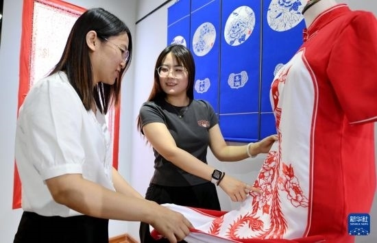 5月31日，在衡水市阜城縣一家剪紙工作室，游客在觀賞帶有剪紙?jiān)氐钠炫邸? width=