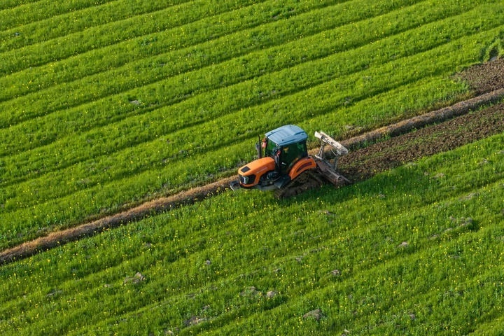 2024年3月19日，在湖南省常德市鼎城區(qū)謝家鋪鎮(zhèn)港中坪村，村民駕駛農(nóng)機翻耕田地（無人機照片）。新華社記者 陳思汗 攝
