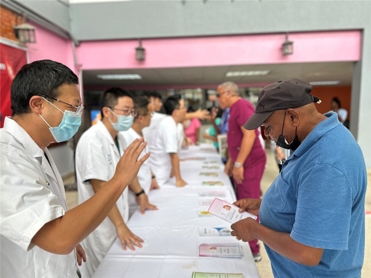 援圭醫(yī)療隊(duì)隊(duì)員們?cè)趩?dòng)儀式上為當(dāng)?shù)孛癖姺职l(fā)宣傳手冊(cè)。中國(guó)援助圭亞那醫(yī)療隊(duì)供圖