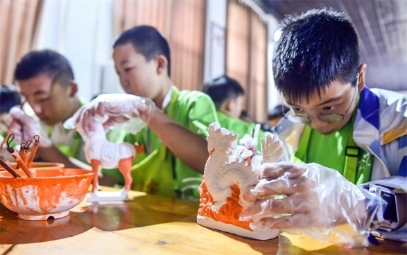 小朋友們?cè)诼尻柺忻辖騾^(qū)朝陽鎮(zhèn)南石山村體驗(yàn)唐三彩素胎施釉技藝。圖片來源：視覺中國