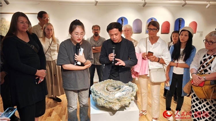 參展人、景德鎮(zhèn)陶瓷大學設計藝術學院副院長余劍峰（中）向來賓介紹參展作品。人民網(wǎng)記者 殷淼攝