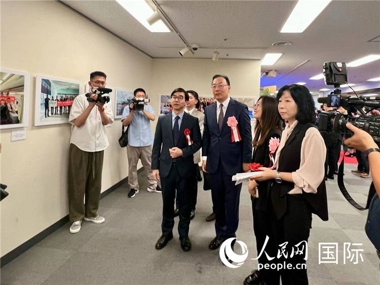 中國國際航空日韓地區(qū)支社支社長馮力為中國駐日本大使館臨時代辦施泳等嘉賓介紹展出圖片。人民網(wǎng) 許可攝