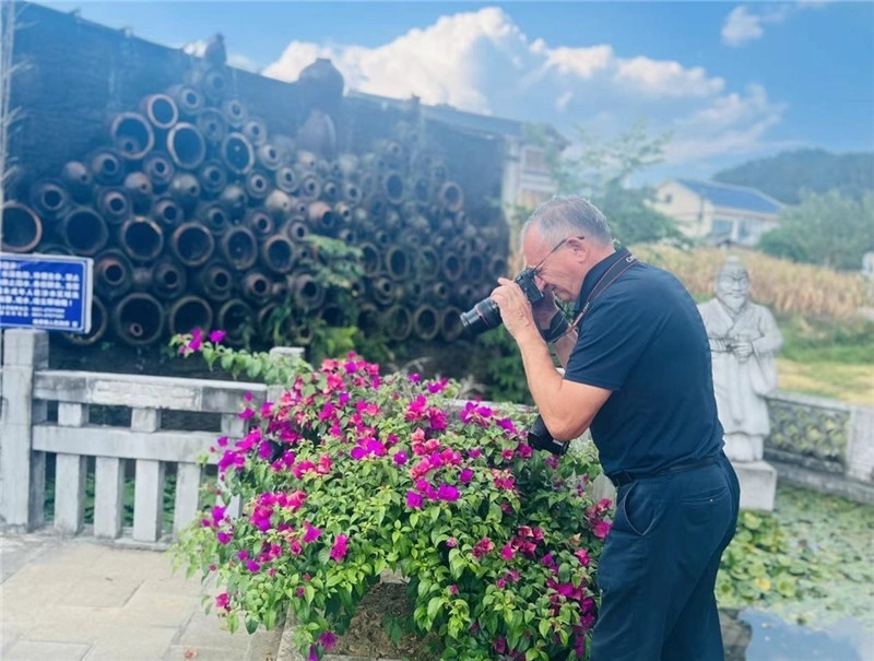 遠(yuǎn)處黔北民居錯(cuò)落有致，近處一只黑色的蝴蝶穿梭于粉紫色三角梅花叢間隙，與俄羅斯“大歐亞”總編輯弗拉基米爾·別列日內(nèi)赫的鏡頭玩起了捉迷藏，“你追我逃，不亦樂乎”。（張亞欣攝）