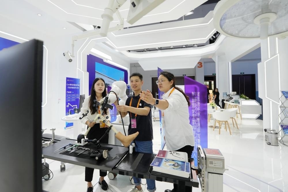 9月11日，一位媒體記者（中）在2024年服貿(mào)會國家會議中心會場體驗北京納通科技集團有限公司的膝關(guān)節(jié)置換手術(shù)機器人。新華社記者鞠煥宗 攝