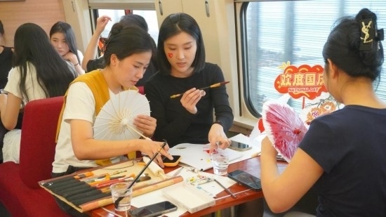 10月1日，旅客們?cè)贕1634次列車上給油紙傘作畫(huà)。新華社記者周義 攝