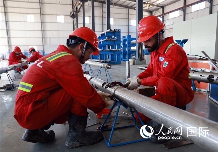 中伊員工共同在檢修鉆井設備。人民網(wǎng)記者管克江攝