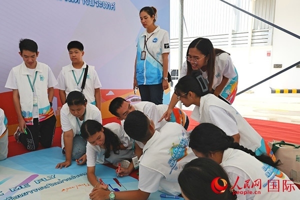 泰國(guó)學(xué)生在開(kāi)營(yíng)儀式展板上繪制圖案。人民網(wǎng)記者 白元琪攝