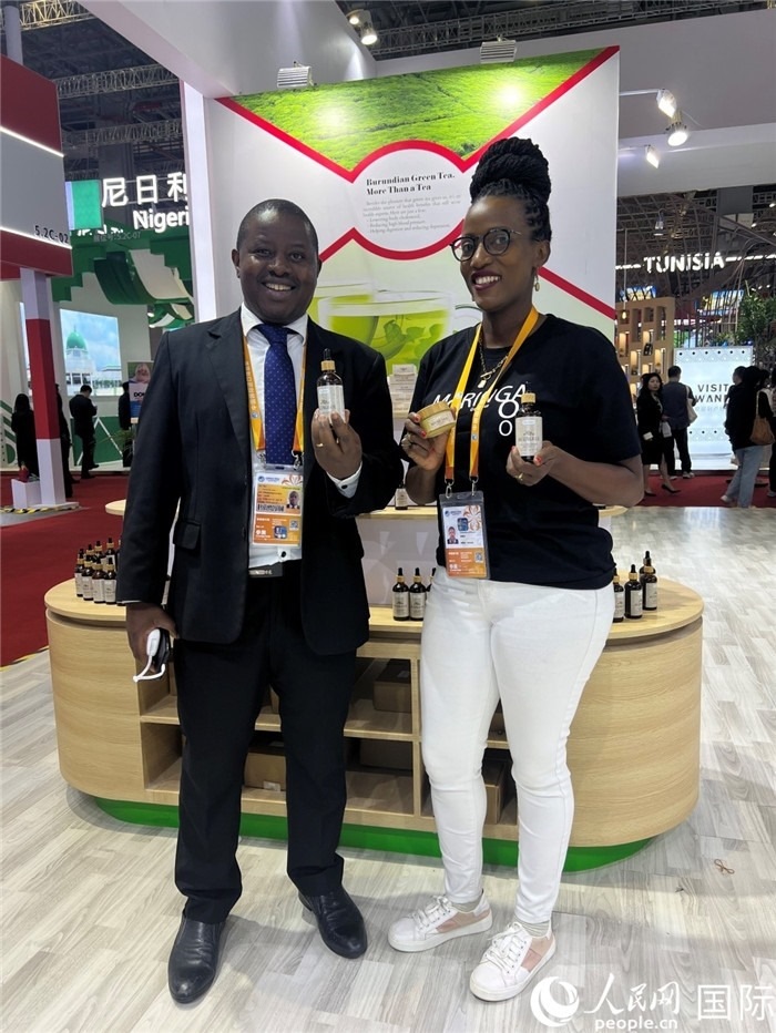 6月6日，布隆迪駐華大使館一等參贊布利馬索·阿爾弗雷德 (左，Bulimaso Alfred) 和參展商卡馬里扎·埃斯特拉 (Kamariza Estella) 在第七屆中國國際進口博覽會布隆迪館展示當(dāng)?shù)厣a(chǎn)的辣木油。（人民網(wǎng) 艾里士 攝）