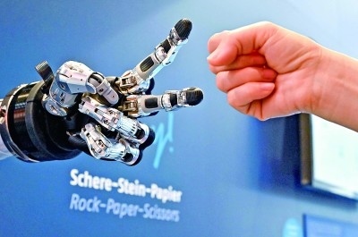 在德國漢諾威工博會上，參觀者與一款智能機器人進行“石頭剪子布”游戲。新華社發(fā)