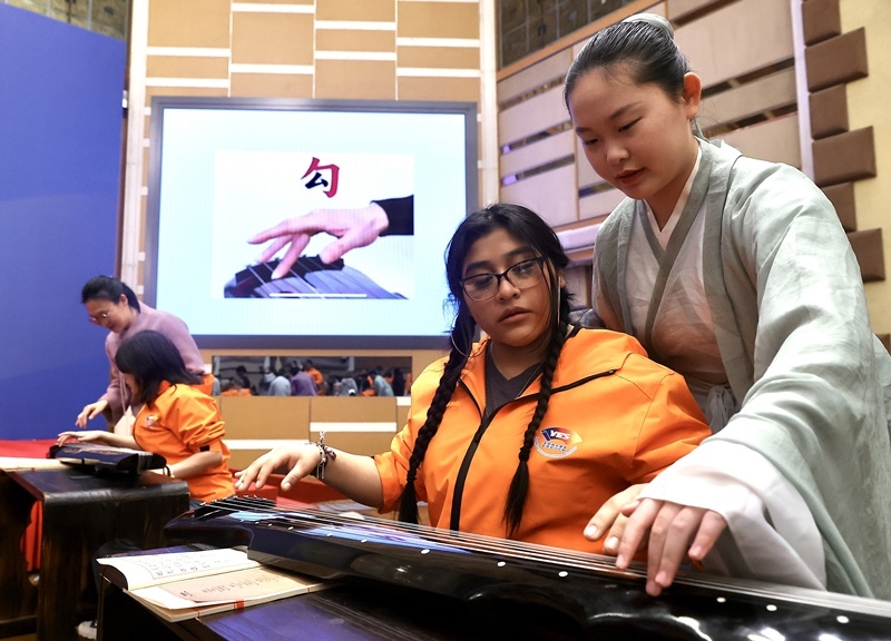 2024年3月20日，美國華盛頓州中學(xué)生代表團(tuán)北京大學(xué)交流活動在北京大學(xué)英杰交流中心舉行。圖為來自華盛頓州的中學(xué)生體驗(yàn)古琴。