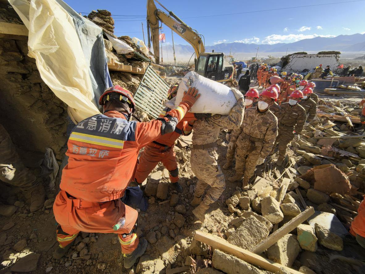 1月11日，定日縣長所鄉(xiāng)古榮村，應急消防等救援人員排隊接力搶運掩埋在倒塌房屋下的群眾財物。人民日報記者楊翹楚攝
