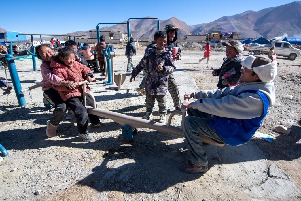 1月11日，在定日縣措果鄉(xiāng)塘仁村安置點，西藏星光社會工作服務中心志愿者和孩子們一起玩耍，進行災后心理疏導。人民網(wǎng)記者 翁奇羽攝
